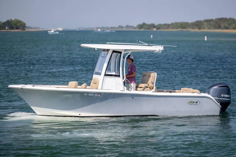 Slide: The Image of 2018 Sea Hunt Ultra 235 SE boat cruising on a calm lake with a person at the helm. - 5