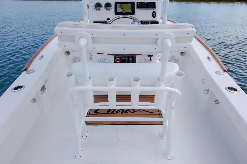 Slide: The Image of 2017 Chaos 21 Tarpon Bay boat interior with helm and rod holders on calm water. - 23