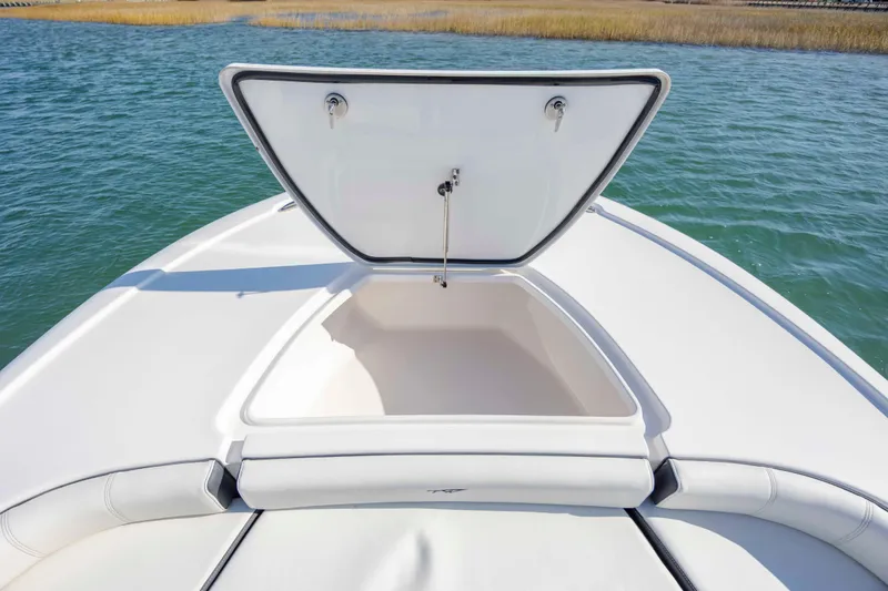 Slide: The Image of 2024 Tidewater 2500 Carolina Bay boat with open storage compartment on calm water. - 11