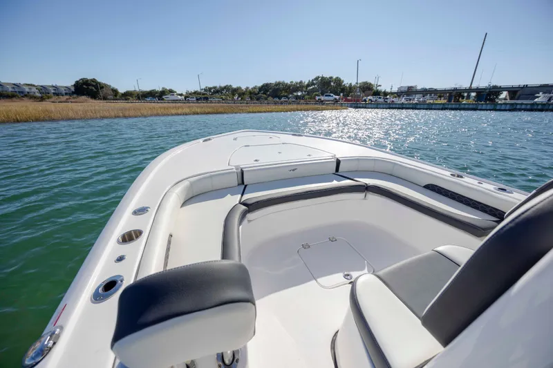 Slide: The Image of 2024 Tidewater 2500 Carolina Bay boat interior on calm water, showcasing seating and deck design. - 14