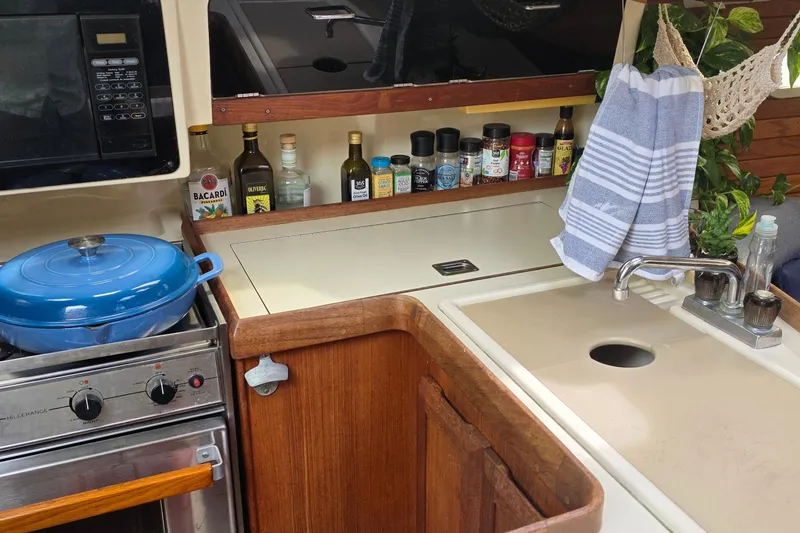 Slide: The Image of Compact kitchen in a 1995 Hunter 336 sailboat with stove, sink, and spices. - 10