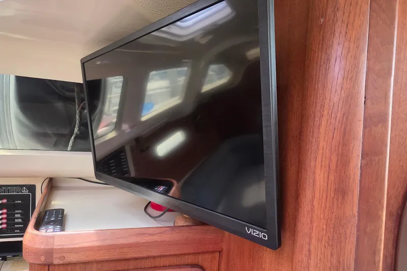 Slide: The Image of Flat-screen TV inside a 1995 Hunter 336 sailboat cabin, mounted on wooden paneling. - 16