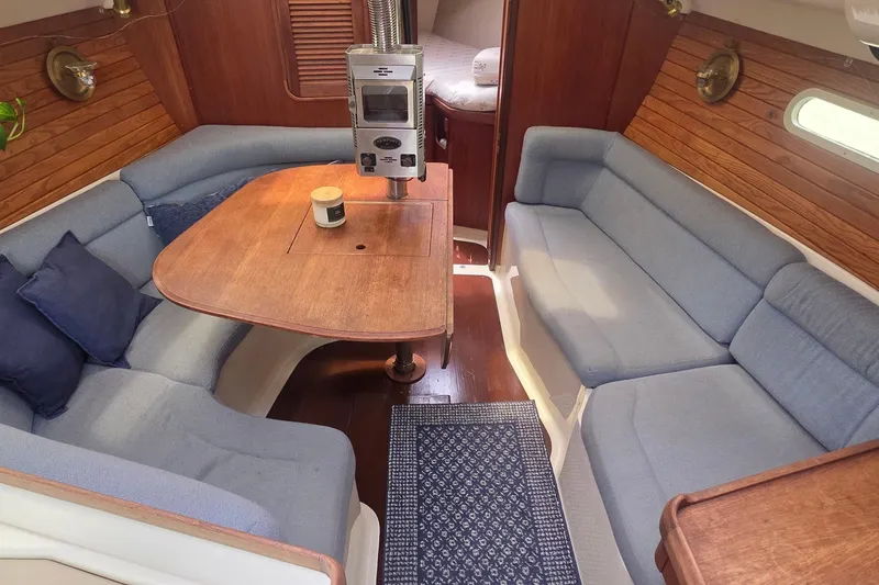 Slide: The Image of Cozy interior of a 1995 Hunter 336 sailboat with blue seating and wooden table. - 4