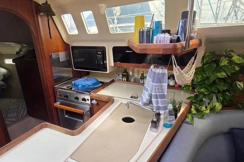 Slide: The Image of Cozy 1995 Hunter 336 yacht kitchen with stove, microwave, and lush greenery. - 9