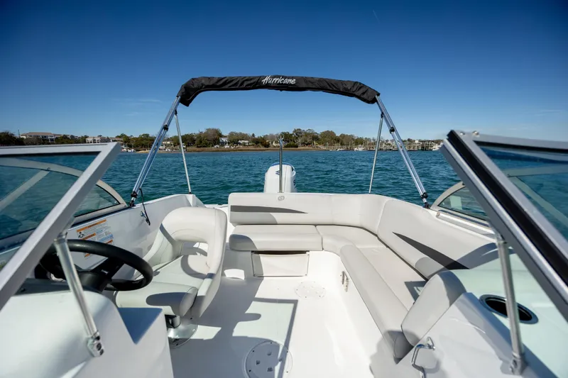 Slide: The Image of 2023 Hurricane SunDeck 187 OB boat interior with seating, steering wheel, and open water view. - 11