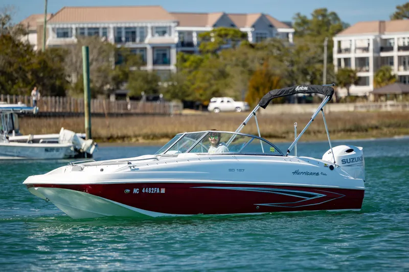 Slide: The Image of 2023 Hurricane SunDeck 187 OB boat cruising on a sunny day near waterfront buildings. - 3