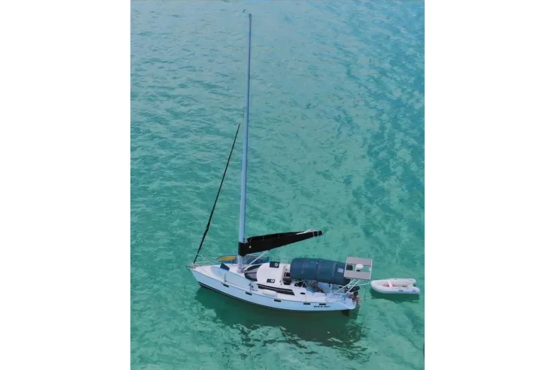 Slide: The Image of Sailboat Hunter Vision 36 (1993) anchored in clear turquoise water, with a small dinghy nearby. - 1