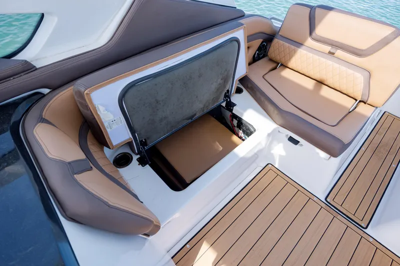 Slide: The Image of 2024 Yamaha Boats 275SD interior seating with storage compartment open, featuring tan upholstery. - 14