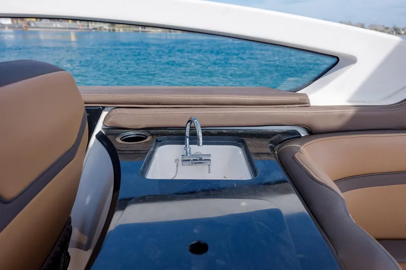 Slide: The Image of 2024 Yamaha Boats 275SD interior with sleek sink and luxurious seating by the water. - 16