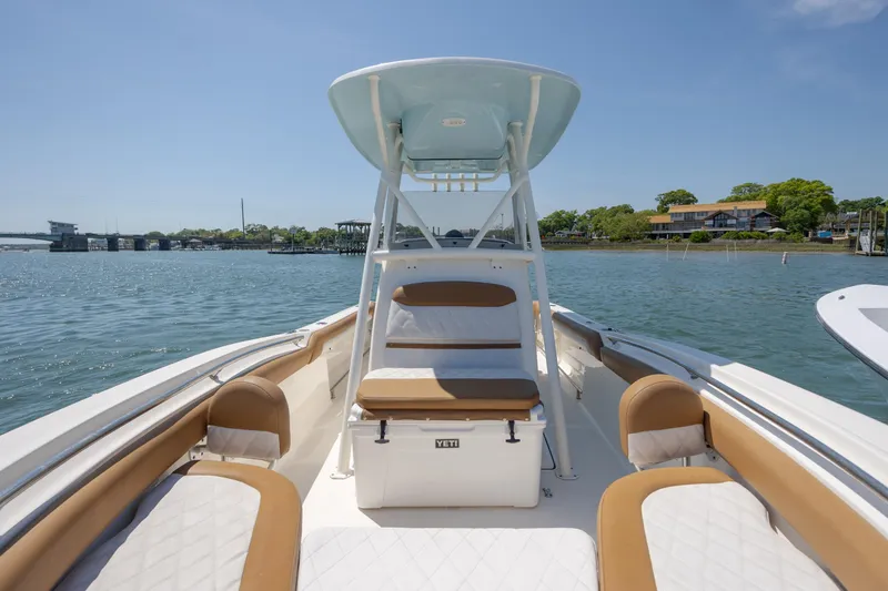 Slide: The Image of 2019 Pioneer 222 Sportfish boat interior with seating, on calm water near shoreline. - 12