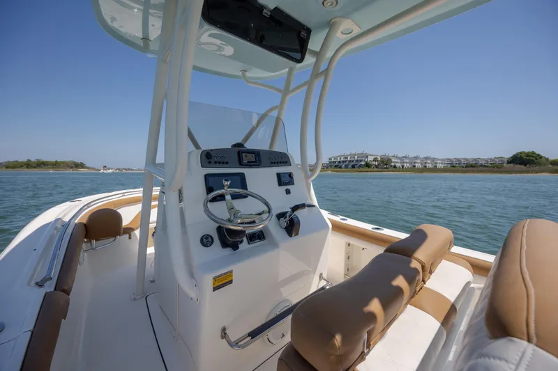 Slide: The Image of 2019 Pioneer 222 Sportfish boat interior with steering console, on calm water near shoreline. - 24
