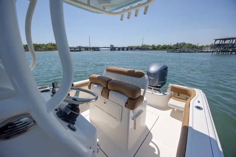 Slide: The Image of 2019 Pioneer 222 Sportfish boat on water, featuring helm and seating, under clear sky. - 25