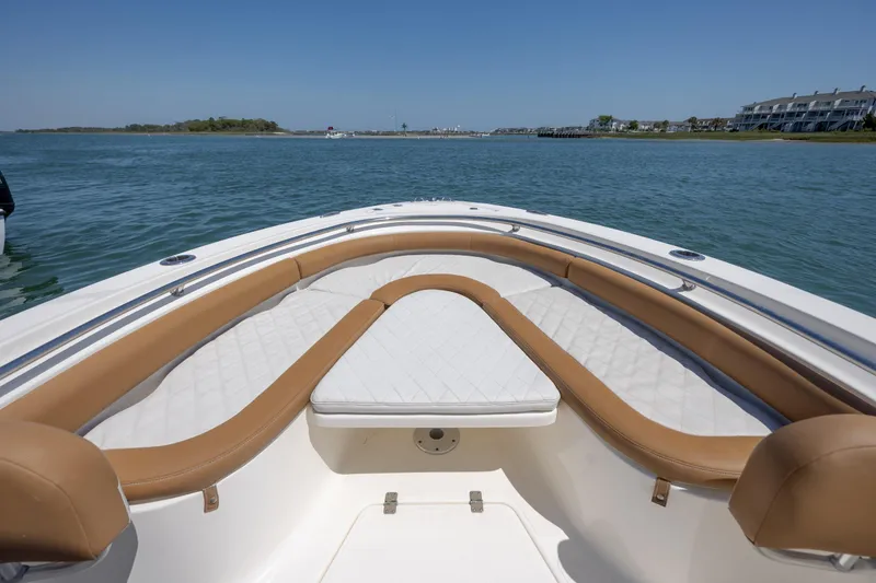 Slide: The Image of 2019 Pioneer 222 Sportfish boat interior with cushioned seating on calm water. - 9