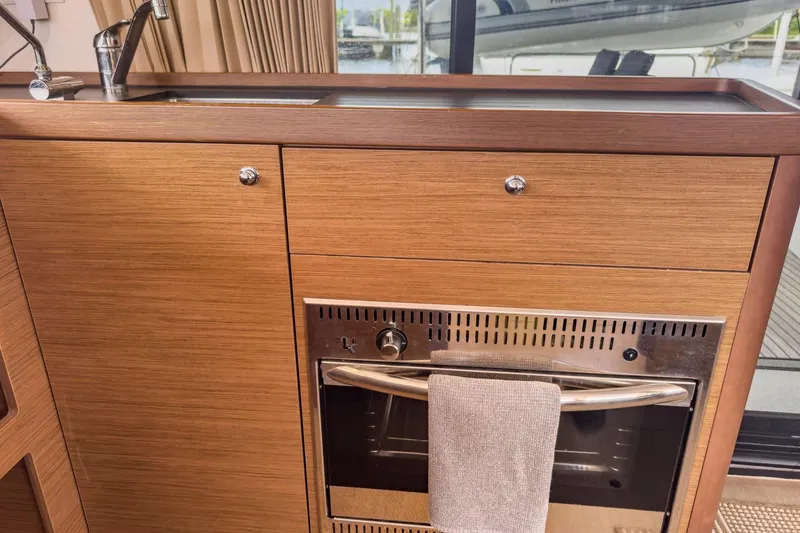 Slide: The Image of Modern kitchen area in a 2020 Lagoon 42 yacht with wood cabinetry and stainless steel oven. - 24