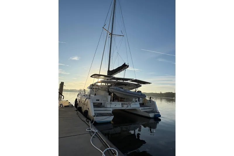 Slide: The Image of 2020 Lagoon 42 catamaran docked at sunrise, reflecting on calm water. - 91