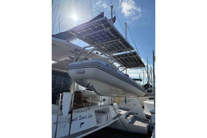 Slide: The Image of 2020 Lagoon 42 catamaran with solar panels and dinghy, docked under a sunny sky. - 103