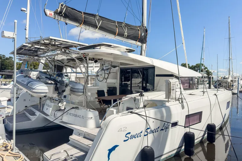 Slide: The Image of 2020 Lagoon 42 catamaran docked, featuring solar panels and a dinghy, named "Sweet Sweet Life." - 2