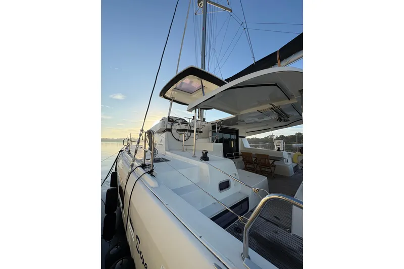 Slide: The Image of 2020 Lagoon 42 catamaran docked at sunrise, showcasing sleek design and spacious deck. - 95
