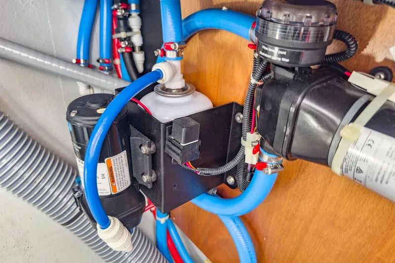 Slide: The Image of Electrical and plumbing system inside a 2020 Lagoon 42 yacht, featuring blue hoses and components. - 89