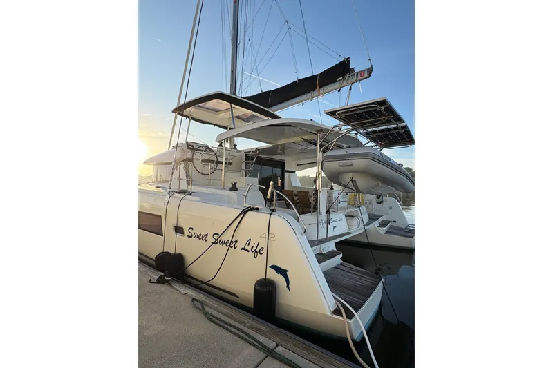 Slide: The Image of 2020 Lagoon 42 catamaran docked at sunset, featuring solar panels and an inflatable boat. - 92