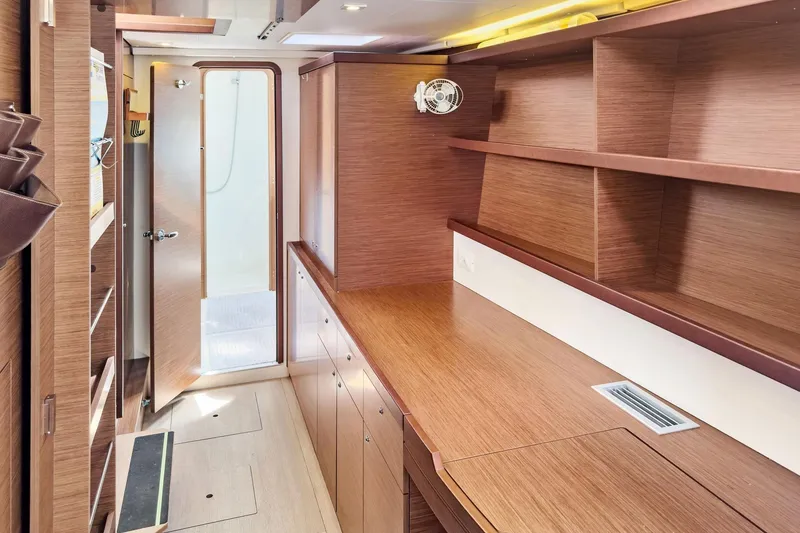 Slide: The Image of Interior of 2020 Lagoon 42 yacht with wooden cabinetry and open door to bathroom. - 49