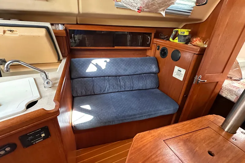 Slide: The Image of Interior of a 2002 Hunter 306 sailboat with blue cushioned seating and wooden cabinetry. - 25