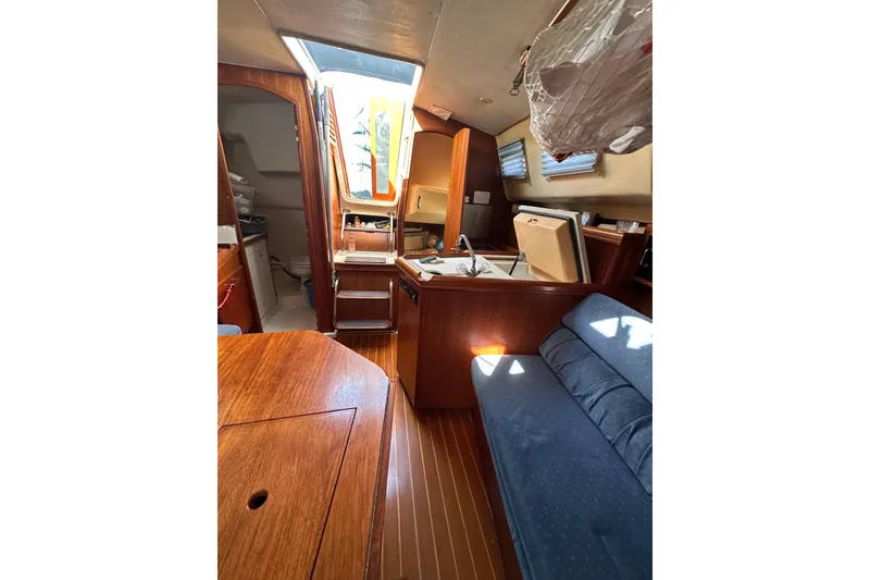 Slide: The Image of Interior of a 2002 Hunter 306 sailboat, featuring wood finishes and compact living space. - 32
