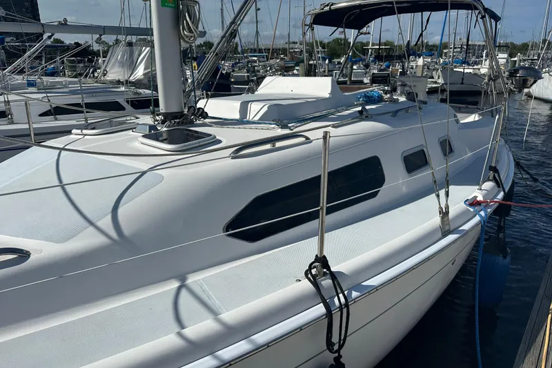 Slide: The Image of 2002 Hunter 306 sailboat docked at marina, featuring sleek white design and spacious deck. - 5