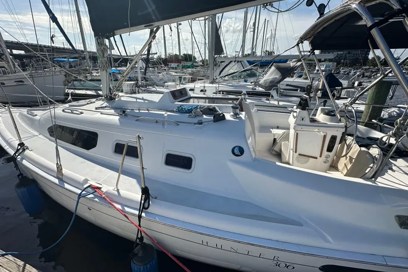 Slide: The Image of Hunter 306 sailboat from 2002 docked at a marina, showcasing its deck and cockpit. - 7