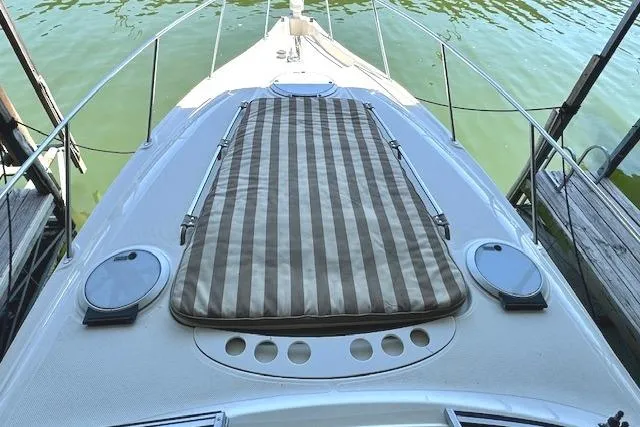 Slide: The Image of 2001 Maxum 3000 SCR boat with striped sun pad on deck, docked on calm water. - 15