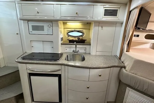Slide: The Image of 2001 Maxum 3000 SCR yacht interior kitchen with sink, stove, microwave, and storage cabinets. - 23