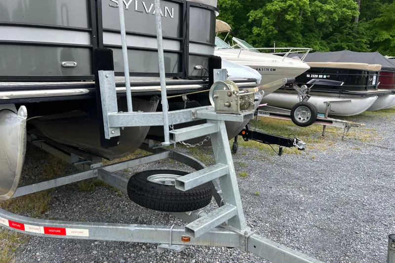 Slide: The Image of 2021 Sylvan L5 DLZ pontoon boat on trailer, parked on gravel lot. - 15