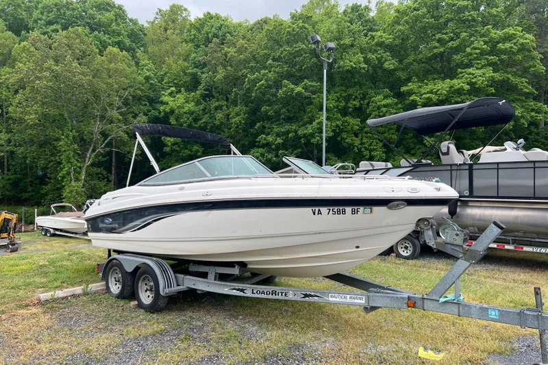 The Image of 2005 Chaparral 204 SSi boat on trailer, parked outdoors with lush green trees in background. - 0