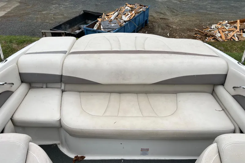 Slide: The Image of 2005 Chaparral 204 SSi boat interior with white cushioned seating and debris in the background. - 10