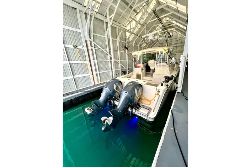 Slide: The Image of 2017 Grady-White Express 330 boat docked in a covered marina with dual outboard engines. - 2