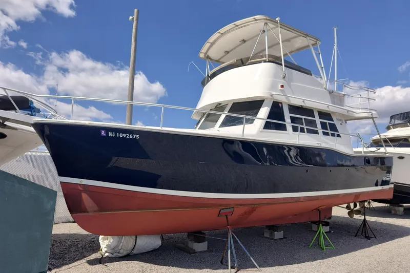 The Image of 2000 Mainship 390 Trawler boat on dry dock under a clear blue sky. - 1