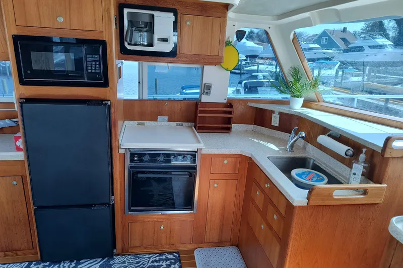 Slide: The Image of Interior of 2000 Mainship 390 Trawler kitchen with appliances and wooden cabinetry. - 10