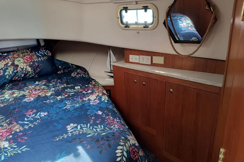 Slide: The Image of Cozy cabin interior of 2000 Mainship 390 Trawler with floral bedding and wooden cabinetry. - 16