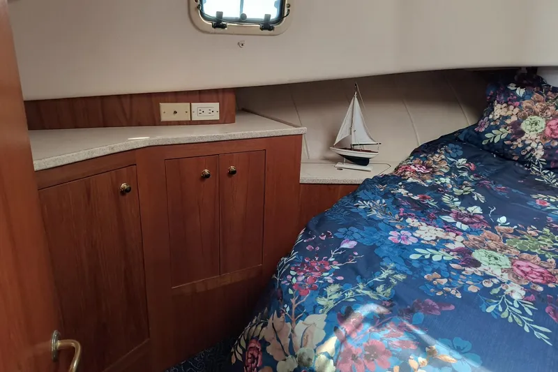 Slide: The Image of Cozy cabin interior of 2000 Mainship 390 Trawler with floral bedding and wooden cabinetry. - 17