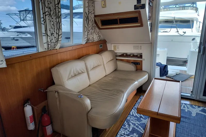 Slide: The Image of Interior of 2000 Mainship 390 Trawler with beige sofa, wooden table, and nautical decor. - 5