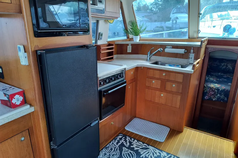Slide: The Image of Cozy kitchen in 2000 Mainship 390 Trawler with wood cabinetry, appliances, and a window view. - 7