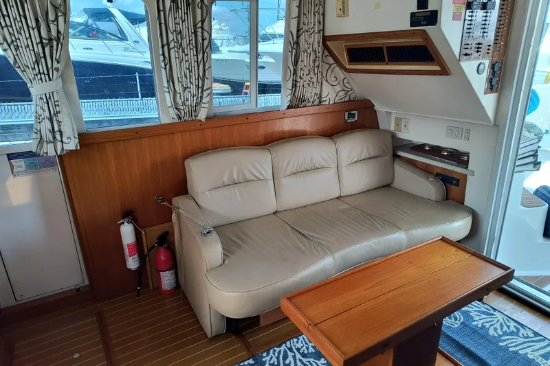 Slide: The Image of Interior of 2000 Mainship 390 Trawler with beige sofa, wooden table, and nautical decor. - 9