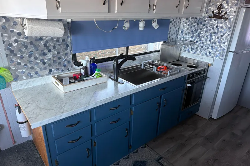 Slide: The Image of Kitchen interior of a 1996 Gibson Sport 41 boat with blue cabinets and marble countertops. - 2