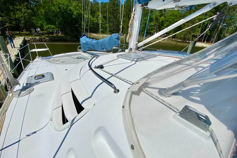 Slide: The Image of 1998 Manta 40 sailboat deck with rigging, docked near lush greenery. - 104