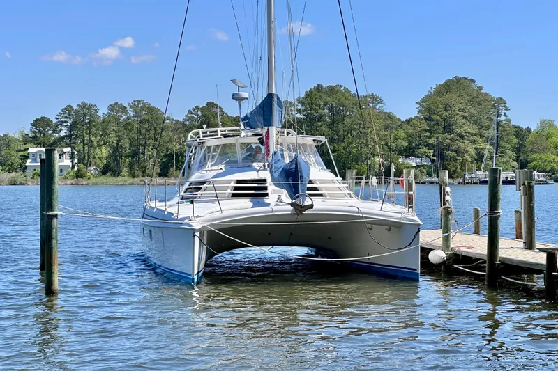 Slide: The Image of 1998 Manta 40 catamaran docked on a serene lake with lush trees. - 106