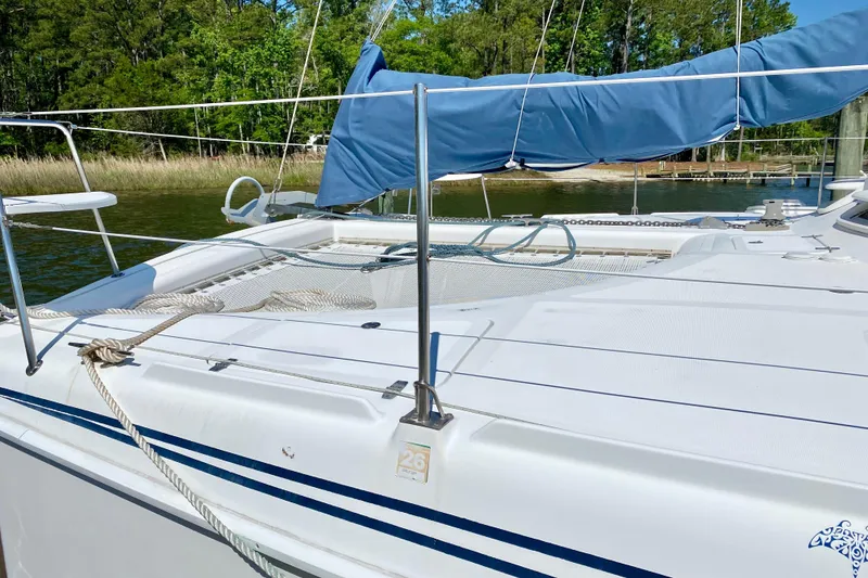 Slide: The Image of Sailboat deck of 1998 Manta 40 with blue sail cover, docked near lush greenery. - 2