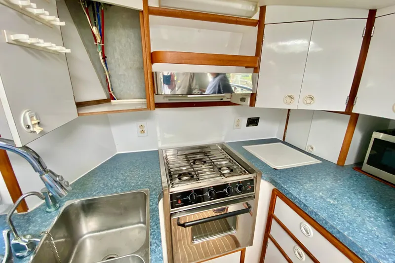Slide: The Image of Compact kitchen in a 1998 Manta 40 boat with stove, sink, and cabinets. - 29