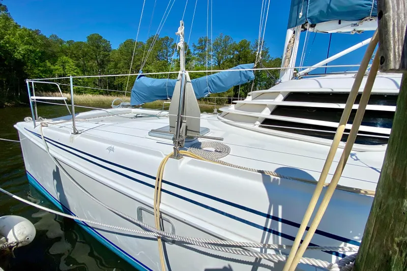Slide: The Image of Sailboat Manta 40, 1998 model, docked with blue sail covers, surrounded by trees. - 3