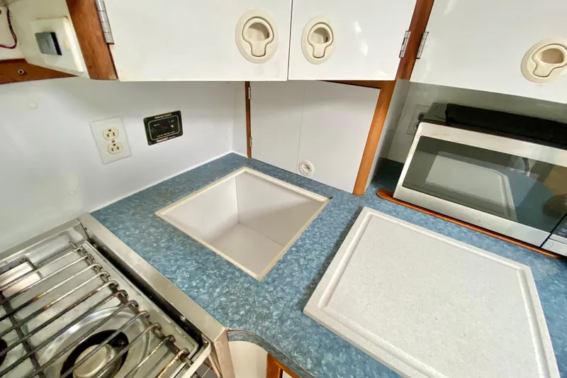 Slide: The Image of Compact kitchen area in a 1998 Manta 40 boat with stove, sink, and microwave. - 31
