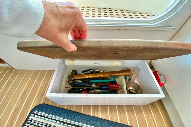 Slide: The Image of Hand opening a wooden toolbox on a 1998 Manta 40 boat, revealing various tools. - 34